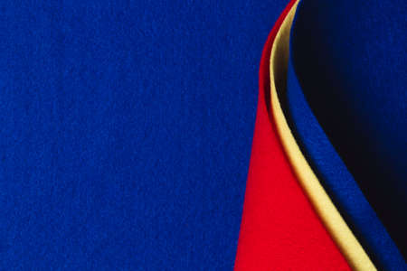 Abstract geometric felt texture background. Creative geometric curved felt textile background in blue, yellow and red colors. Top view, copy spaceの写真素材