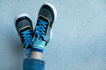 Kid wearing different pair of socks. Child legs up in mismatched socks on gray background. Odd Socks day, Anti-Bullying Week. Down syndrome awareness conceptの写真素材