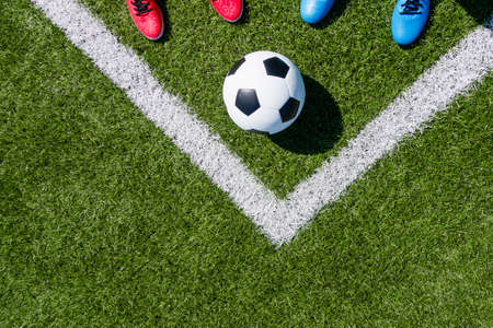Soccer football background. Soccer ball and two pair of football sports shoes on artificial turf soccer field. Top viewの写真素材