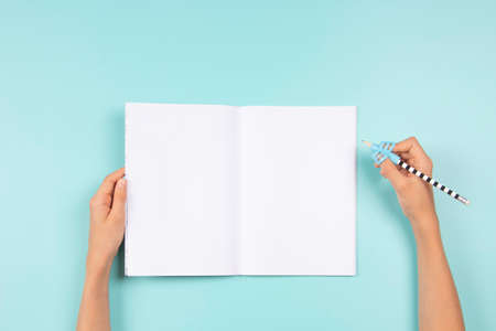 Kid hands using pencil with silicone three finger pen holder. Hand holding pencil with handwriting correction tool and open blank notebook. Top view. School, learning difficulties, writing, educationの写真素材