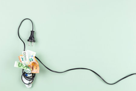 Euro banknotes are tightly wrapped with electric power cable cord. Energy efficiency, power consumption, rising electricity price and expensive energy conceptの写真素材