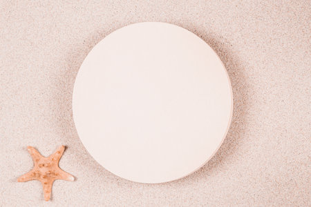 Empty beige round platform podium for cosmetics or products presentation on natural beige beach sand background. Wavy curved ornaments on sand, drawn by hand. Top viewの写真素材