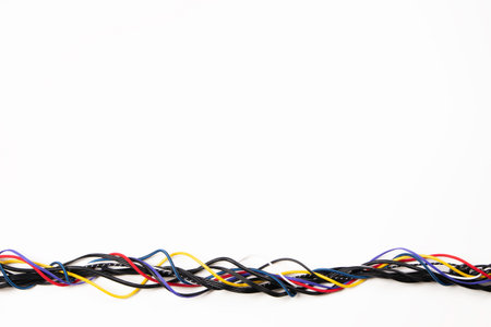 Many colorful electrical cord cables twist together into single frame line on white background. Top...