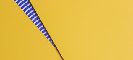 Abstract geometric bright colored papers texture background. Yellow background and striped paper with blue and white stripes between. Top view, flat layの写真素材