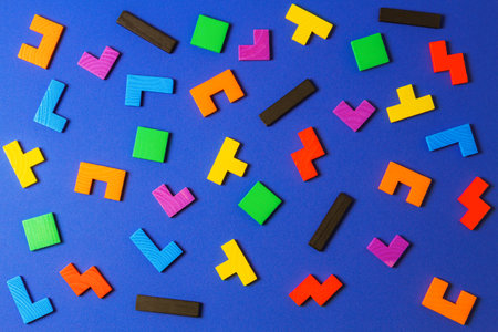 Different colorful shapes wooden puzzle blocks on blue background. Geometric shapes in different colors. Top viewの写真素材
