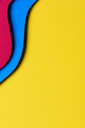 Abstract colored paper texture background. Minimal paper cut style composition with layers of geometric shapes and lines in red and light blue colors on yellow background. Top viewの写真素材