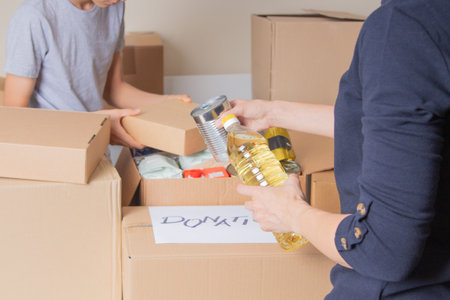 Volunteers collecting grocery products into donation boxes. Food donation, charity, food bank, help...