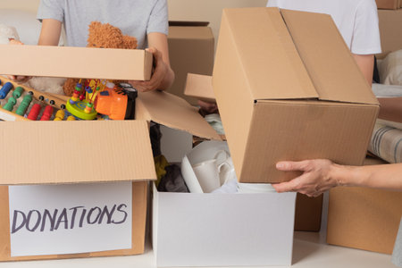 Volunteers collect donations for charity to help low income families. Donation boxes with clothes,...