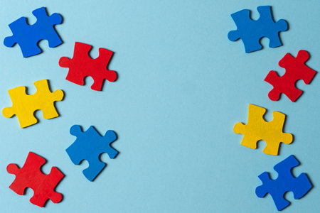Blue, yellow, red pieces of puzzle on light blue frame background. World autism awareness day concept. Top view, copy spaceの写真素材