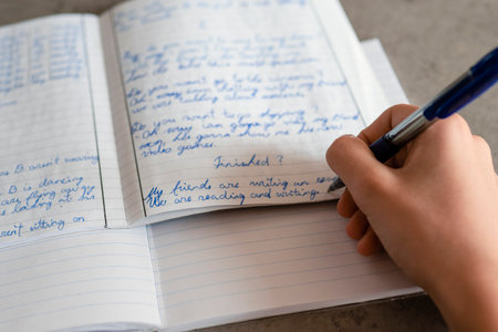 Teenage boy writing with pen in notebook. Kid doing school homework. Education, learning...