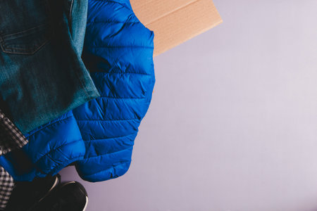 Cardboard box with clothes on gray background. Clothing for donation, charity, sell online. Top view, copy spaceの写真素材