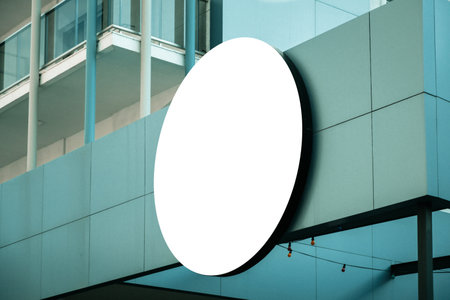 Empty white circle mockup signboard template on modern building wall. Store, shop, office, hotel logo sign mock up outdoorsの写真素材