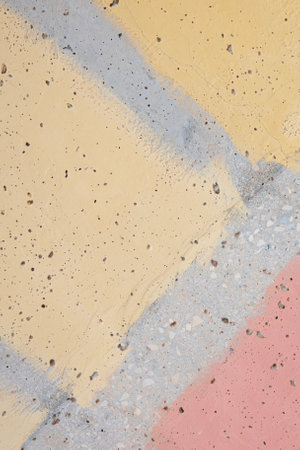 Abstract light yellow and pastel pink painted plaster wall background. Old gray stucco sufface wall background with streaks of paint and paint spraysの写真素材