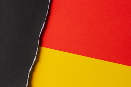 Black grunge ripped torn paper piece with ragged edge on yellow and red color paper background. Top view, copy spaceの写真素材