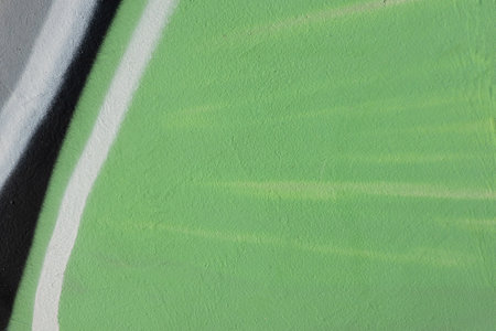 Fragment of old plaster wall with graffiti painting. Part of colorful street art graffiti on wall background. Youth, urban culture. Light green, black, gray, white colorsの写真素材