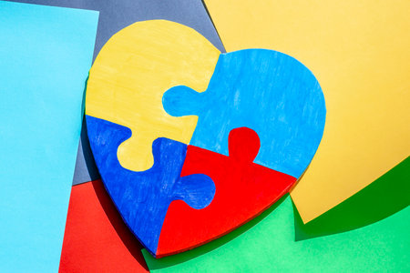 Colorful painted jigsaw puzzle heart on multicolored paper background. World autism awareness day, Autism spectrum disorder concept. Top viewの写真素材