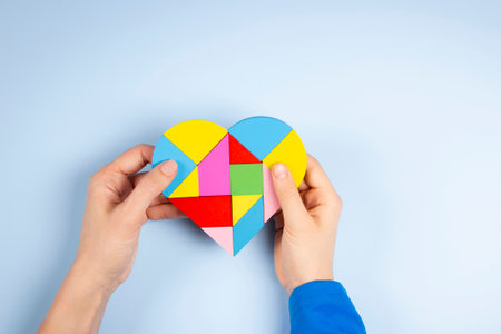 World autism awareness day, Autism spectrum disorder concept. Woman and child hands holding puzzle heart over light blue background. Top viewの写真素材