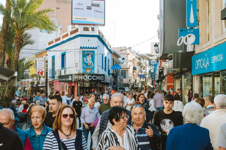 Benidorm, Spain - 01 April, 2023: People relax and enjoy sunny day on the shopping street in Benidorm old town. Crowdy streets of Benidorm. Benidorm - popular Spanish resort near Mediterranean seaのeditorial素材