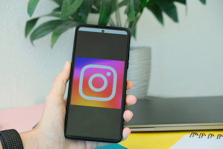 Benidorm, Spain - April 06, 2023: Hand holding smartphone with Instagram application logo on screen...