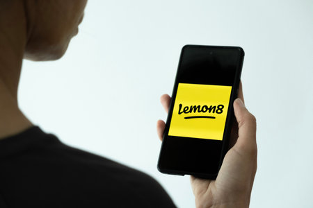 Benidorm, Spain - April 13, 2023: Woman hand holds phone with Lemon8 app. Lemon8 is photo-based app that resembles mixture of Instagram and Pinterest, video and photo-sharing social media appのeditorial素材