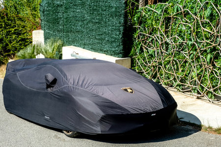 Benidorm, Spain - 06 April, 2023: Lamborghini car covered with black car protective awning. Lamborghini car under protective cover parked near the houseのeditorial素材