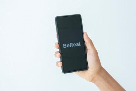 Benidorm, Spain - April 13, 2023: Teenage boy holding smartphone with BeReal mobile phone application. BeReal is photo-sharing social media app that notifies users to post one unfiltered photo dailyのeditorial素材