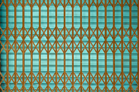 Brown rusty iron grate in front of closed shutter outdoors. Abstract urban backgroundの写真素材