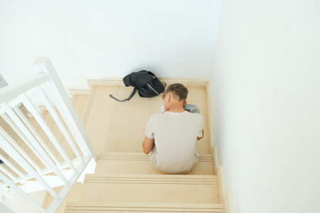 Sad frustrated teenage boy with backpack sitting on stairs alone. Education difficulties, problem with family, emotion, anxiety, depression in adolescence conceptの写真素材
