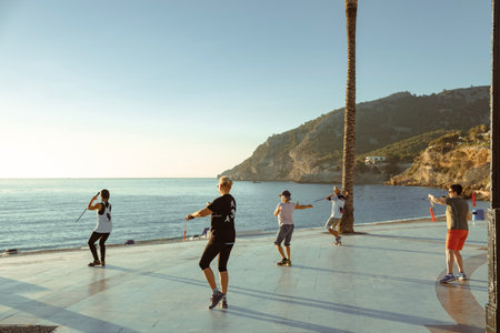 Albir, Spain - April 26, 2023: Active people exercise in the morning in Albir seaside beach...