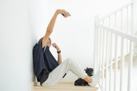 Teenage boy making selfies with his smart phone while sitting on staircaseの写真素材