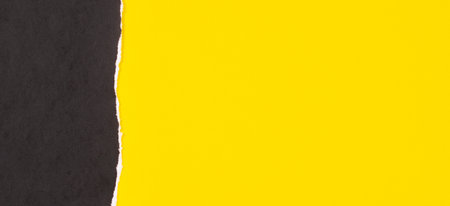 Black grunge ripped torn paper piece with ragged edge on yellow color paper background. Top view, copy spaceの写真素材