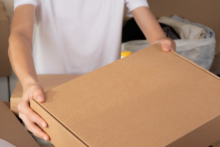 Volunteer hands holding blank cardboard box for donations. Donation, charity, food bank, help for low income, poor families, migrants, refugee, homeless peopleの写真素材