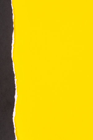 Black grunge ripped torn paper piece with ragged edge on yellow color paper background. Top view, copy spaceの写真素材