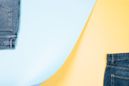 Trendy composition with part of new jeans on light blue and pastel yellow background. Abstract denim background. Denim store, shop, sale, recycling backgroundの写真素材
