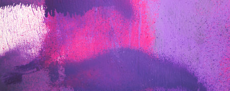 Purple paint strokes and smudges on an pink painted wall background. Abstract wall surface with part of graffiti. Colorful drips, flows, streaks of paint and paint spraysの写真素材