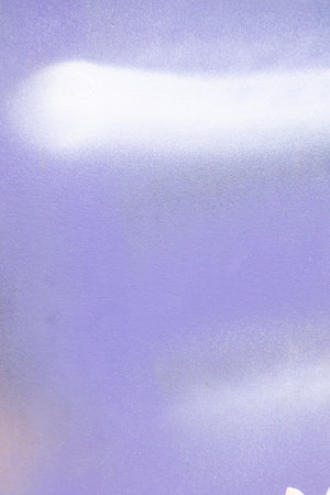 White paint strokes and smudges on purple painted wall background. Abstract wall surface with part of graffiti. Colorful drips, flows, streaks of paint and paint spraysの写真素材