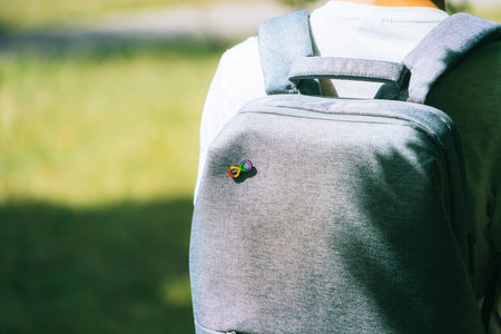 Teenage boy with gray backpack with autism infinity rainbow symbol sign. Worl d autism awareness...