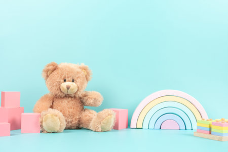 Educational kids toys collection. Teddy bear, wood rainbow, cubes, wooden educational baby toys on pastel blue background. Front viewの写真素材