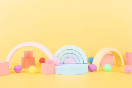 Baby kid toy background. Composition of colorful educational natural wooden toys, rainbow, geometric shapes and round empty podium, platform on pastel yellow background. Front viewの写真素材