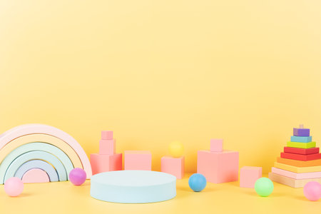 Baby kid toy background. Composition of colorful educational natural wooden toys, rainbow, geometric shapes and round empty podium, platform on pastel yellow background. Front viewの写真素材