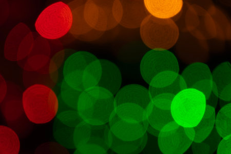 Abstract defocused overlay background. Red green yellow bokeh lights on black background. Defocused city lightsの写真素材