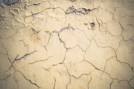 Abstract grunge wall background. Old plastered wall with many cracks. Grungy texture with deep pattern on yellow painted wall.の写真素材