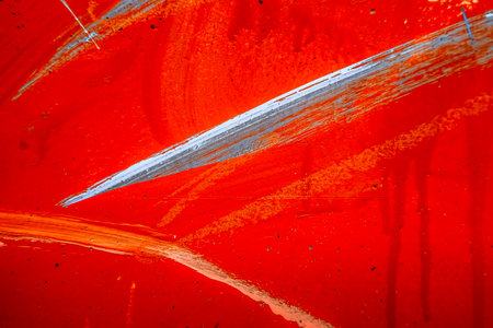 Messy paint strokes and smudges on an old red grunge wall background. White, black, orange color...
