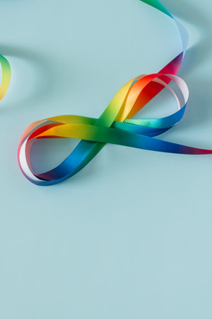 Autism acceptance month, Autism awareness day concept. Rainbow colors ribbons in shape of infinity loop on blue background. Infinity is symbol of autism disorder, adhd, neurodiversityの写真素材