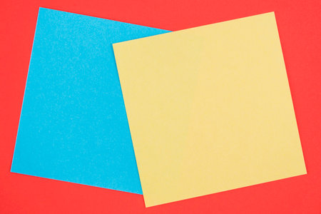 Blank memo square notes on background. Blank yellow and blue colored memo notes on red background backgroundの写真素材
