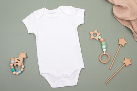 White baby grow bodysuit and natural wooden educational toys on a green background. Mockup template of newborn onesie suitable for baby boys and girls. Top viewの写真素材