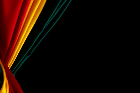 Black History Month, Juneteenth background. Red, yellow, green colors drapery, silk flag on black satin background. Top viewの写真素材