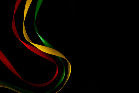 Black History Month, Juneteenth background. Red, yellow, green satin ribbons floating on black silk background. Top viewの写真素材