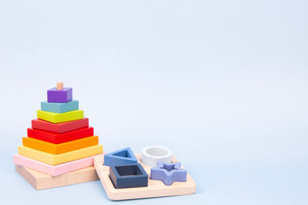 Natural educational toys for early childhood development. Wooden stacking pyramid and geometric shapes board on blue backgroundの写真素材
