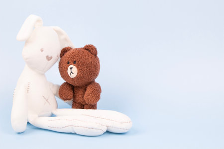 Sad white toy bunny and plush teddy bear comforting each other. Emotional support, friendship, childhood trauma, empathy conceptの写真素材